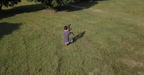 Drone shot a man hold his camera walk in park Chiang Mai Thailand Stock Footage 100747996