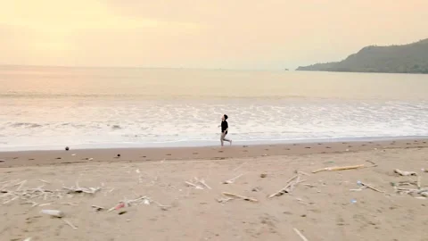 Drone Shot of Man Running on Beach at Sunset Stock Footage 326330247