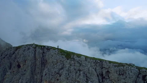 Drone Shot of Man standing on Top of Mountain Ridge in the Clouds at Sunrise Stock Footage 220503567
