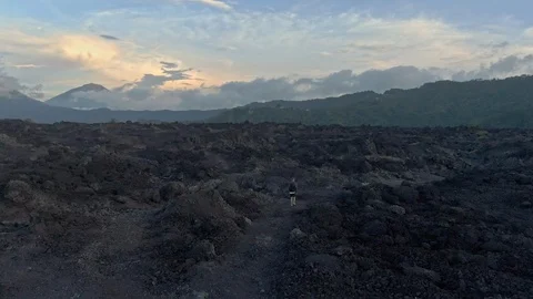 Drone shot of a man walks the fields of frozen lava in Bali Stock Footage 112739651