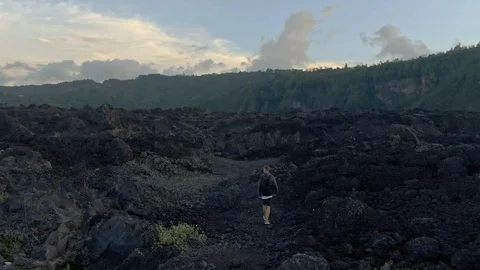 Drone shot of a man walks the fields of frozen lava in Bali Stock Footage 112740035