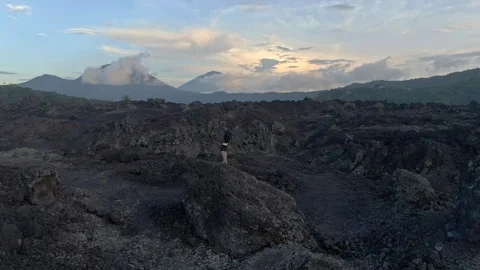 Drone shot of a man walks the fields of frozen lava in Bali Stock Footage 112740061