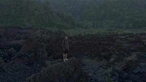 Drone shot of a man walks the fields of frozen lava in Bali Видео 112740501