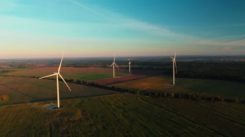 Drone shot of modern wind generators over vast fields at golden hour Stock Footage 337153875