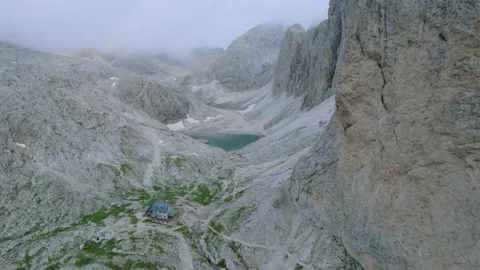 Drone Shot of Mountain Hut with small Lake in alpine Wilderness in the Fog Stock Footage 220503244