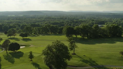 Drone shot moving backwards and tilting up over trees and fairway 스톡 동영상 153696833