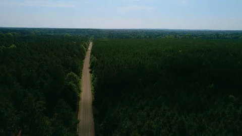 Drone shot moving high to low of a white SUV driving down a dirt road in Vídeo Stock 120827087