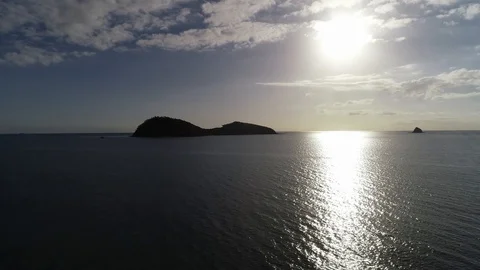 Drone Shot Moving Over Ocean with Island Silhouette in Background Stock Footage 100421557