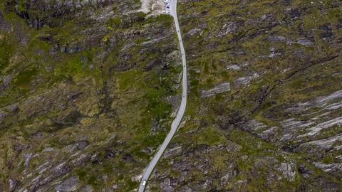 Drone shot of narrow paved road cutting through steep moss-covered mountainsi Foto stock