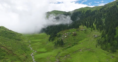 Drone shot of nomadic huts beside mountain stream in foggy alpine valley Stockbeeldmateriaal 346749146