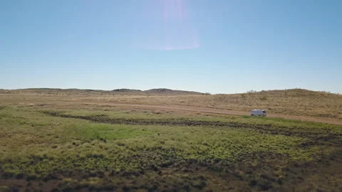 Drone shot orbiting around a white van driving on a asutralian red dirt road thr Stock Footage 294651342