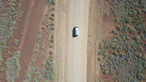 Drone shot orbiting around a white van driving on a asutralian red dirt road thr Stock Footage 294651473