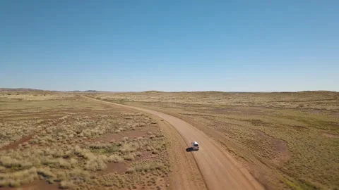 Drone shot orbiting around a white van driving on a asutralian red dirt road thr Stock Footage 294651476