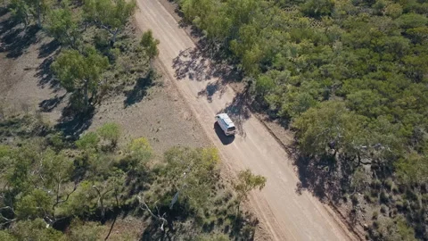 Drone shot orbiting around a white van driving on a asutralian red dirt road thr Video stock 294651767