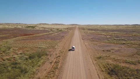 Drone shot orbiting around a white van driving on a asutralian red dirt road thr Stock Footage 294651774