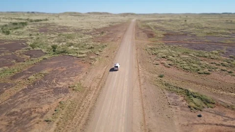 Drone shot orbiting around a white van driving on a asutralian red dirt road thr Video stock 294651942