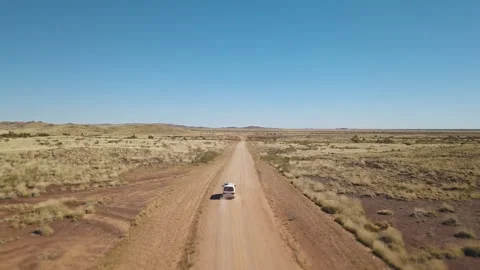 Drone shot orbiting around a white van driving on a asutralian red dirt road thr Stock Footage 294652212