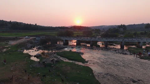 Drone shot over a bridge and a river flowing next to fields in rural India Stock Footage 305259190