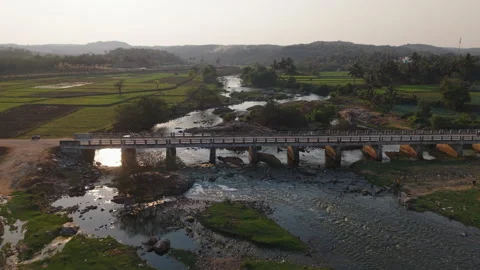 Drone shot over a bridge and a river flowing next to fields in rural India Stock Footage 305261127