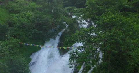Drone shot over glacial waterfall cascading through green mountain ravine in Stock Footage 345275299