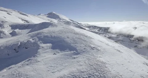 Drone shot over icy crest ridge and ski resort reveal above clouds Stock Footage 104655089