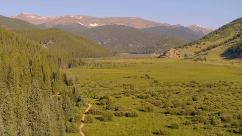 Drone shot over large meadow in the valley of Rocky mountain range Stock Footage 114245994