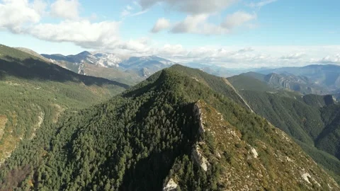 Drone shot over a mountain covered with dense forest in a valley of mountains Stock Footage 228642624