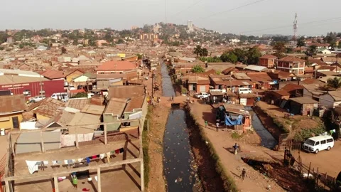 Drone shot over the slums of Uganda, going backwards. Cars cross the river. Stock Footage 201264993