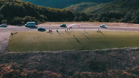 Drone shot of a paraglider taking off of a mountain start. Flying through Stock Footage 265156727