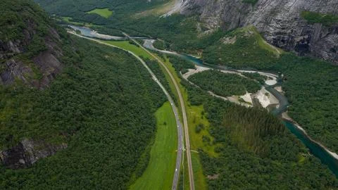 Drone shot of parallel highway and railway cutting through forested valley wi Foto stock