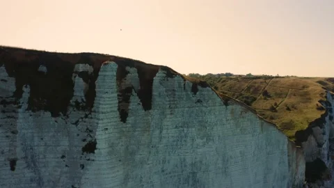 Drone shot passing over a cliff and discovering the land behind Stock Footage 140187371