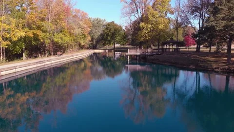 Drone shot of pond in fall reflecting the changing leaves and trees Stock Footage 135472322
