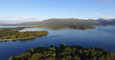 Drone Shot Pulling Away from Scottish Islands over a Vivid Blue Lake Stock Footage 97571860