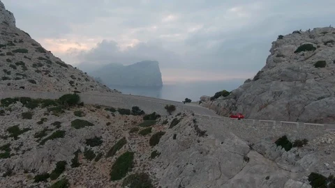 Drone shot of the red car driving on a cliff road in Palm de Mallorca Stock Footage 119580974