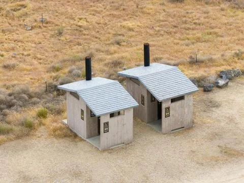 Drone shot reveals two rustic wooden restrooms with gray roofs Stock Photos