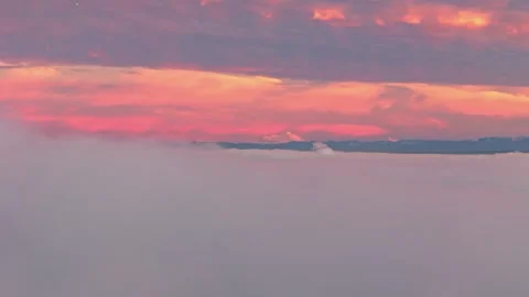 Drone shot rising up from behind clouds to reveal Mount Baker in Washington 動画素材 345522692