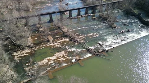 Drone shot of a river with an old bridge, leafless trees and broken branches fal Stock Footage 237031703