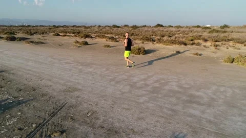 Drone shot of runner jogging in sandy beach desert Video stock 132167029