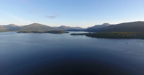 Drone Shot of Scottish Hills Pulling Back over a Deep Blue Loch 스톡 동영상 97571898