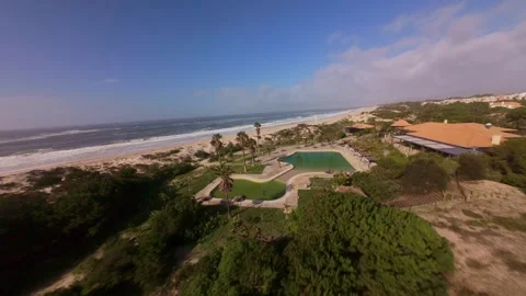 Drone shot shows luxury beachside home with pools amid natural dunes and ocean Stock Footage 345059164