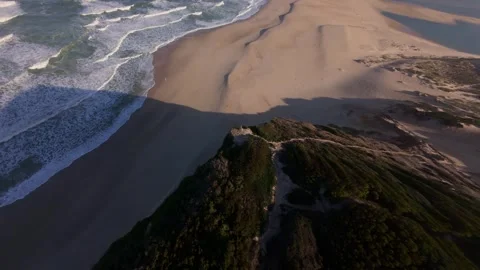 Drone shot soaring above beach, sand dunes, and ocean waves Stock Footage 344580219