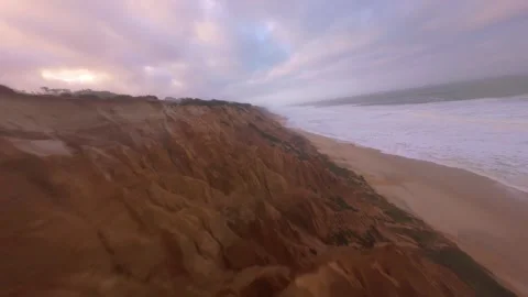 Drone shot soaring over cliffside beach where sea meets earth in raw beauty Stock Footage 345055594