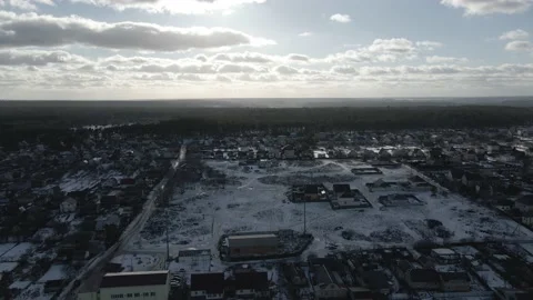 Drone shot of soft sun light from cloudy sky to snowy village and lake. Stock Footage 233920017