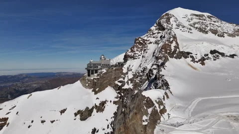 Drone shot of the Sphinx Observatory against the dramatic snowy landscape of Stock Footage 296590691