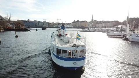 Drone shot in Stockholm following boat with Swedish flag Stock Footage
