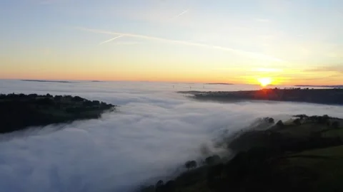 Drone shot of a stunning cloud inversion over mountains, bathed in warm sunset Stock Footage 308459617