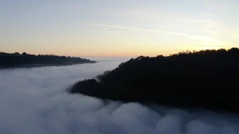 Drone shot of a stunning cloud inversion over mountains, bathed in warm sunset Stock Footage 308460176