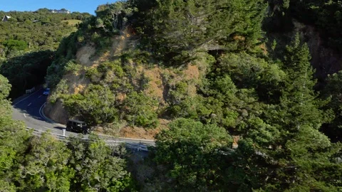 Drone shot tracking black car down hilly country road Stock Footage 88612296