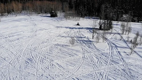 Drone shot tracking a man riding snowmobiling in the snowy forest in the wint Stock Footage 108538179