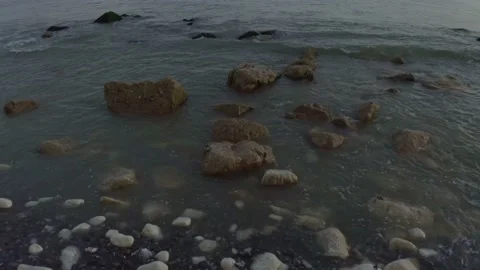 Drone shot tracking out over rocks and waves to reveal horizon Stock Footage 132818167